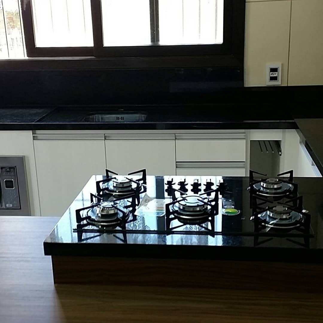 Cozinha com cooktop sobre bancada de pedra preta